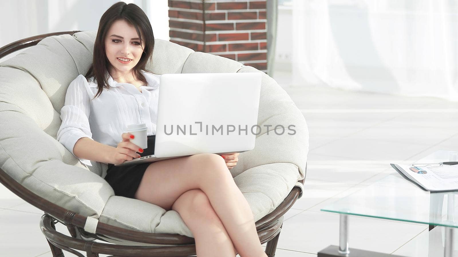 confident business woman with laptop sitting in a comfortable chair.