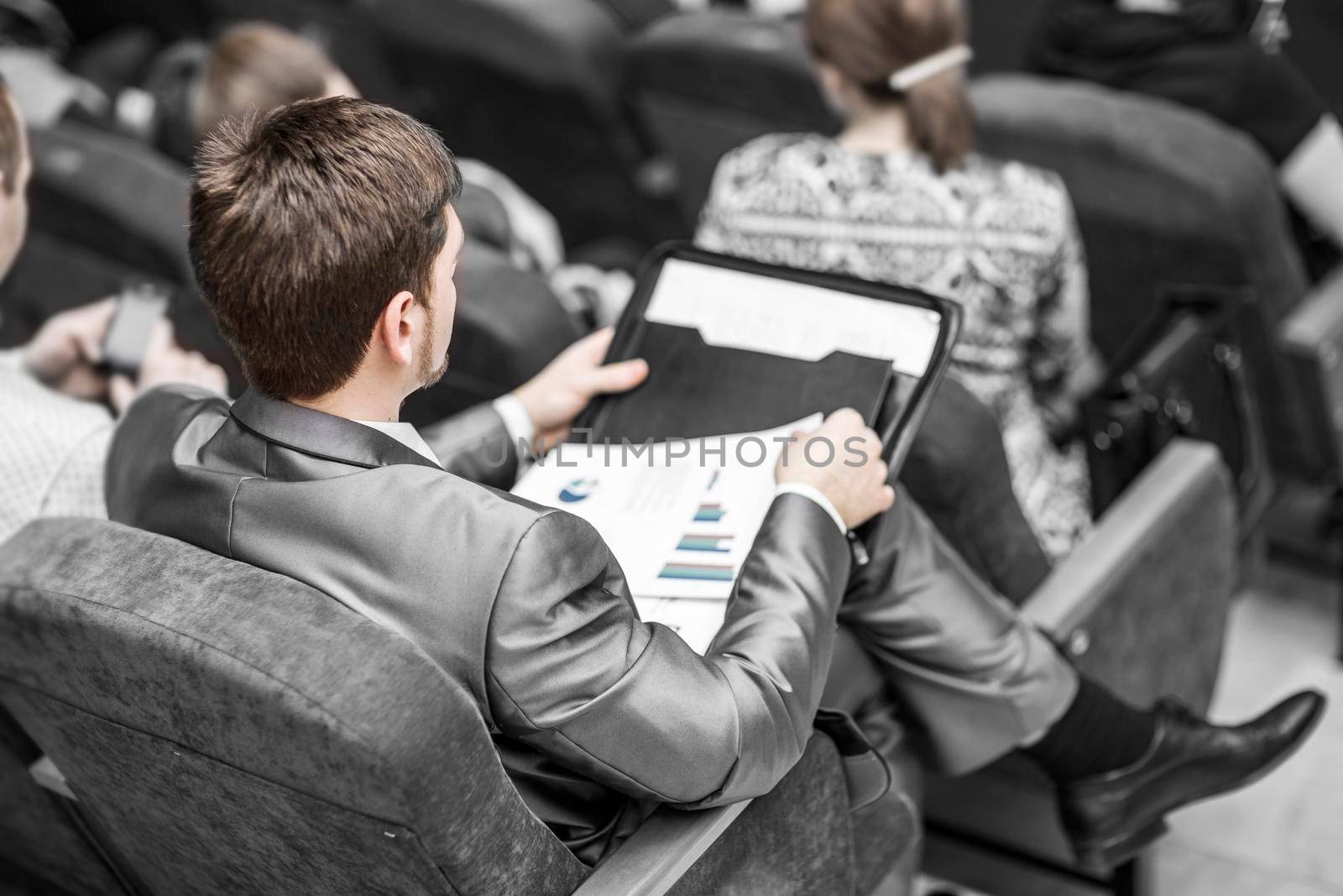 rear view:businessman with financial documents sitting at the lecture hall. business trainings and business conferences