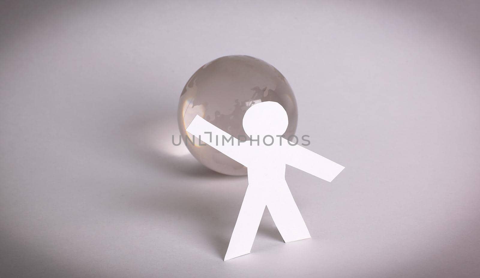 team paper men standing around the glass globe.the concept of unity