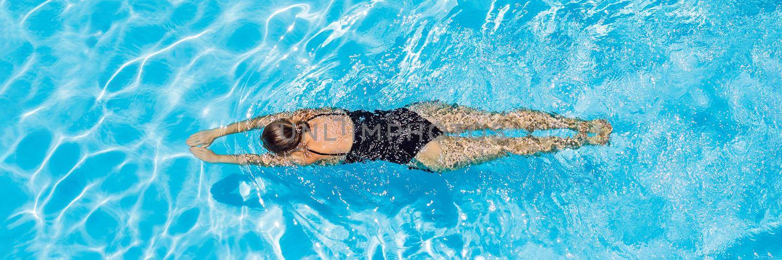 woman with black swimsuit swimming on a blue water pool. BANNER, LONG FORMAT