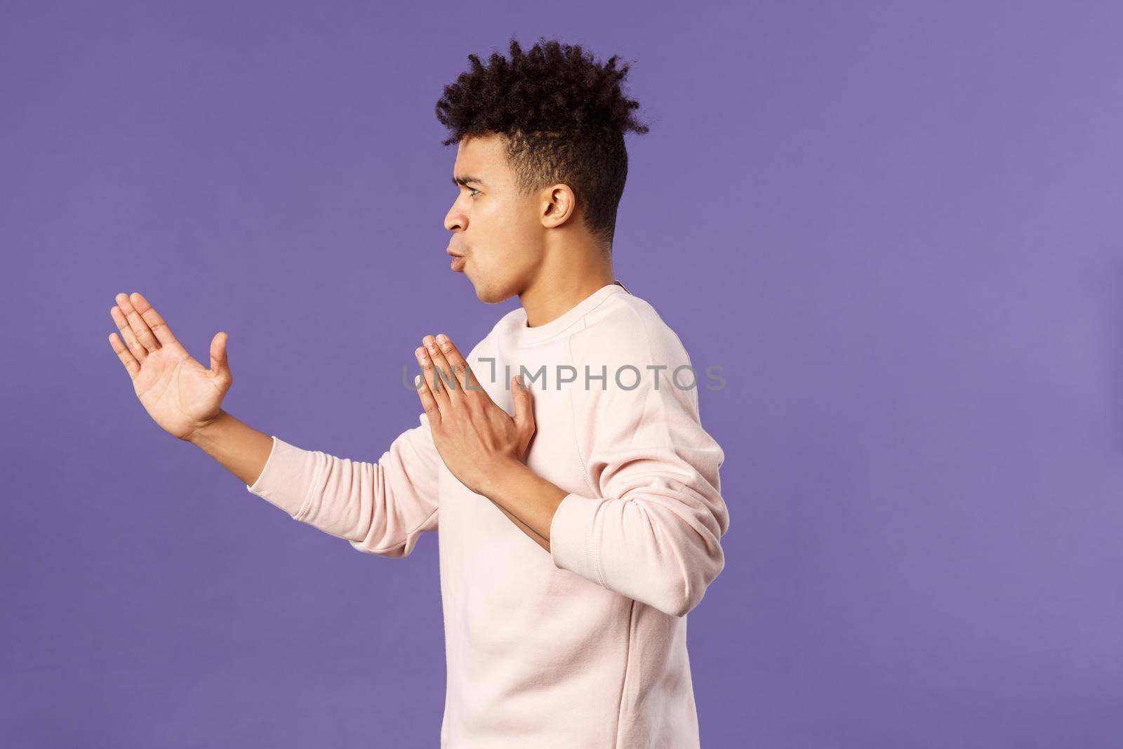 Profile portrait of young hispanic guy with dreads acting like he is ninja or martial arts fighter, practice his kung-fu or taekwondo skills, standing purple background by Benzoix