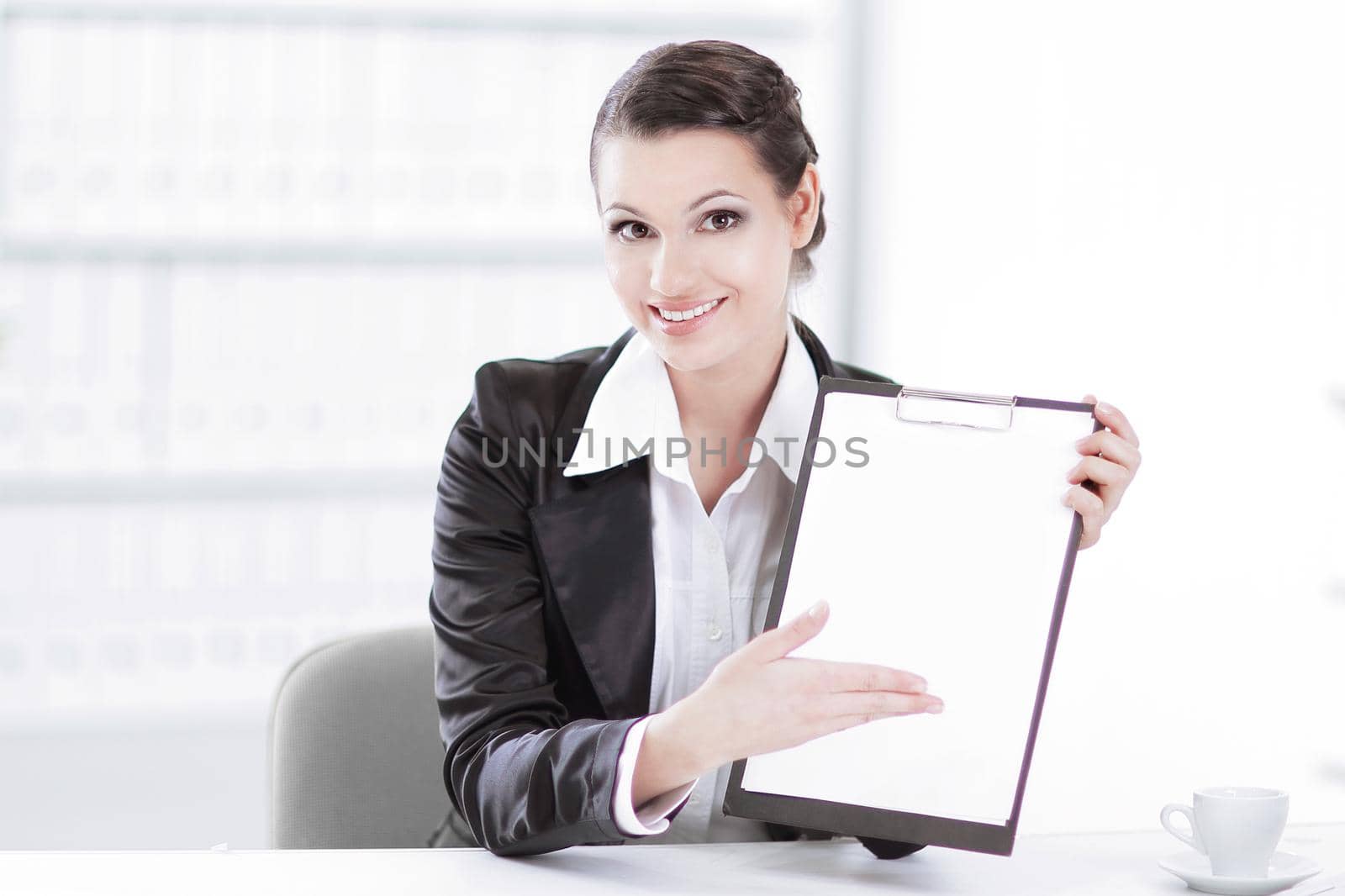 Executive business woman showing blank sheet,sitting at her Desk by SmartPhotoLab