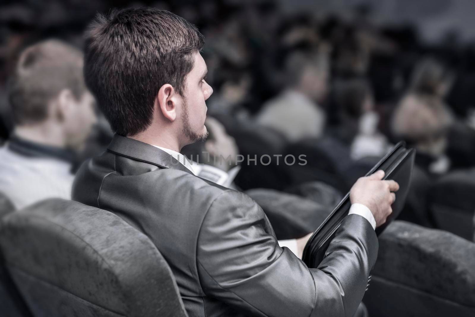 concept of success in business: a successful businessman with a folder for documents, listens to the report sitting in the conference room. by SmartPhotoLab