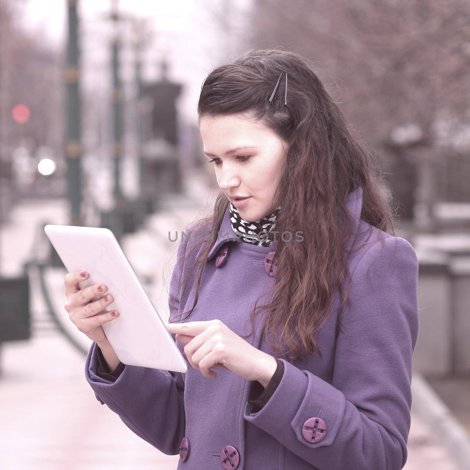 smiling woman using digital tablet standing on city street.