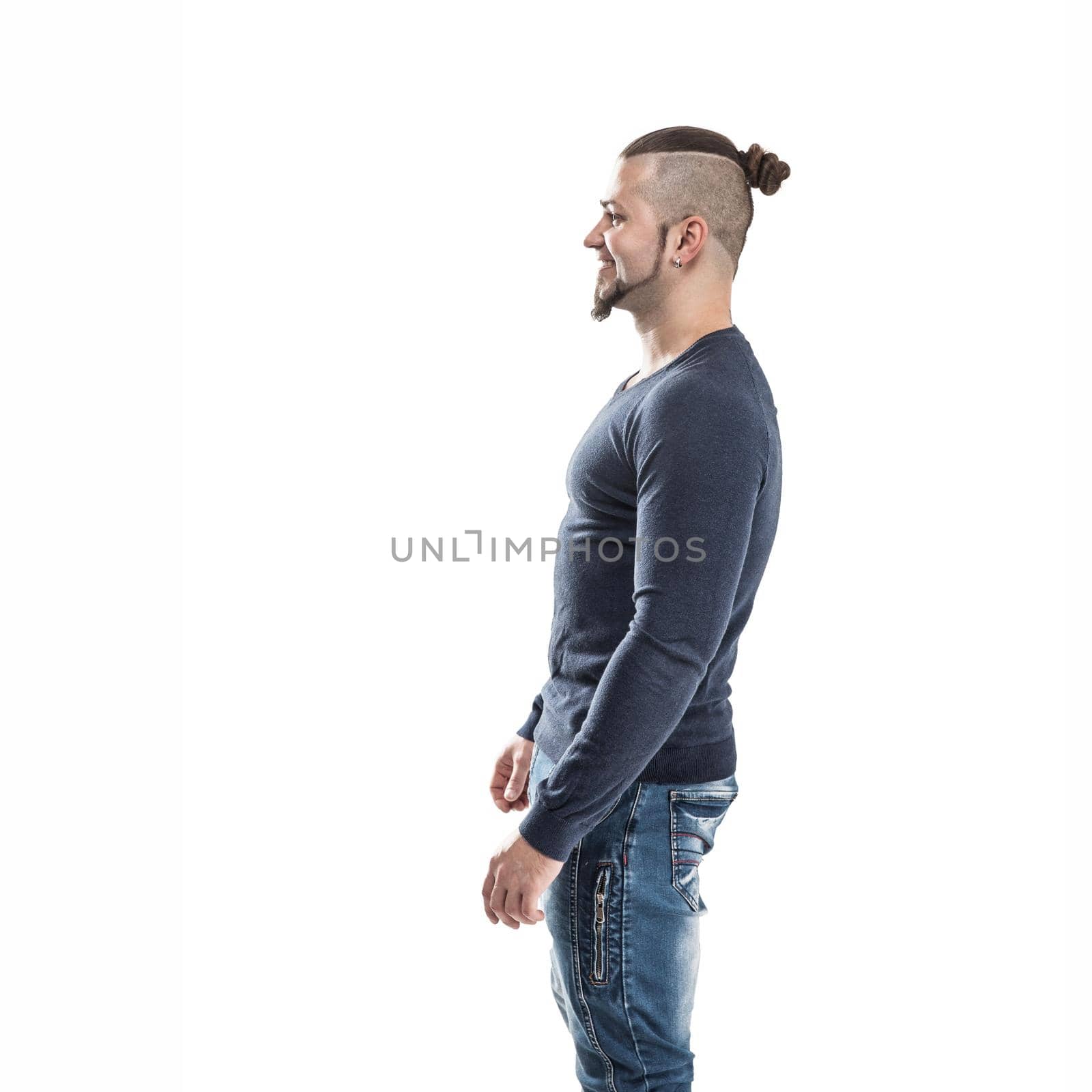side view - the sports guy - a bodybuilder in jeans and a t-shirt on a light background . the photo has a empty space for your text