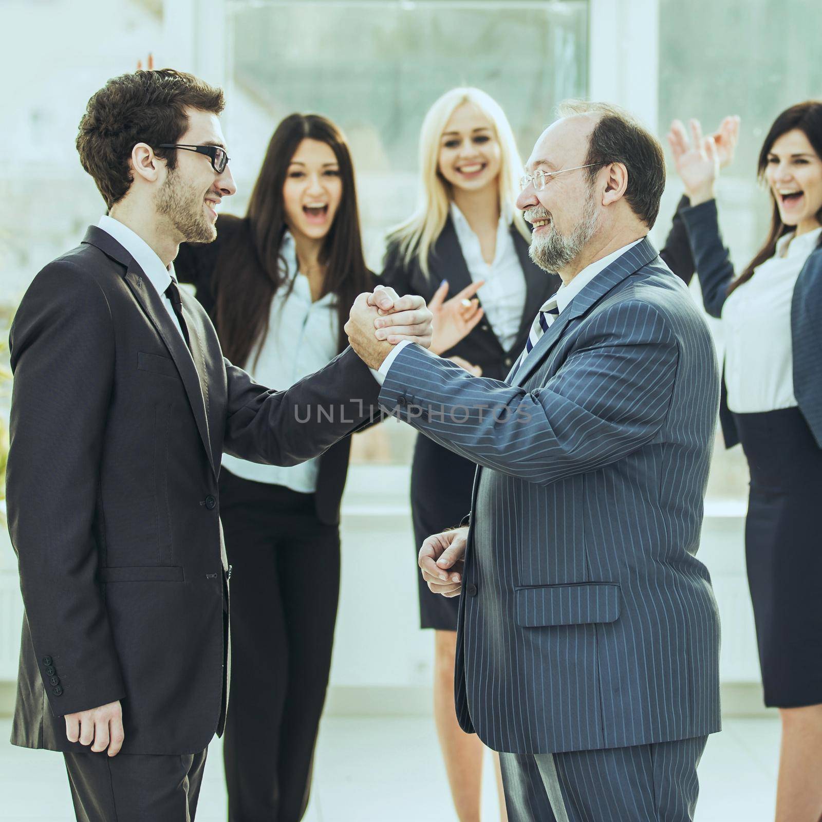 handshake of business partners on background of cheering business team .the photo has a empty space for your text