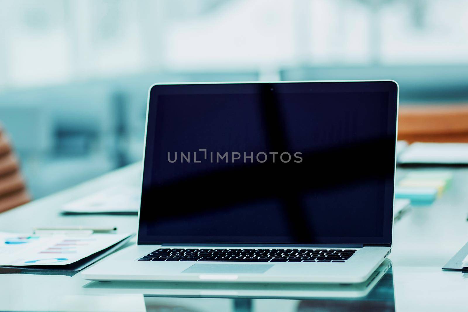 workplace with open laptop and financial documents prepared for meeting business partners by SmartPhotoLab