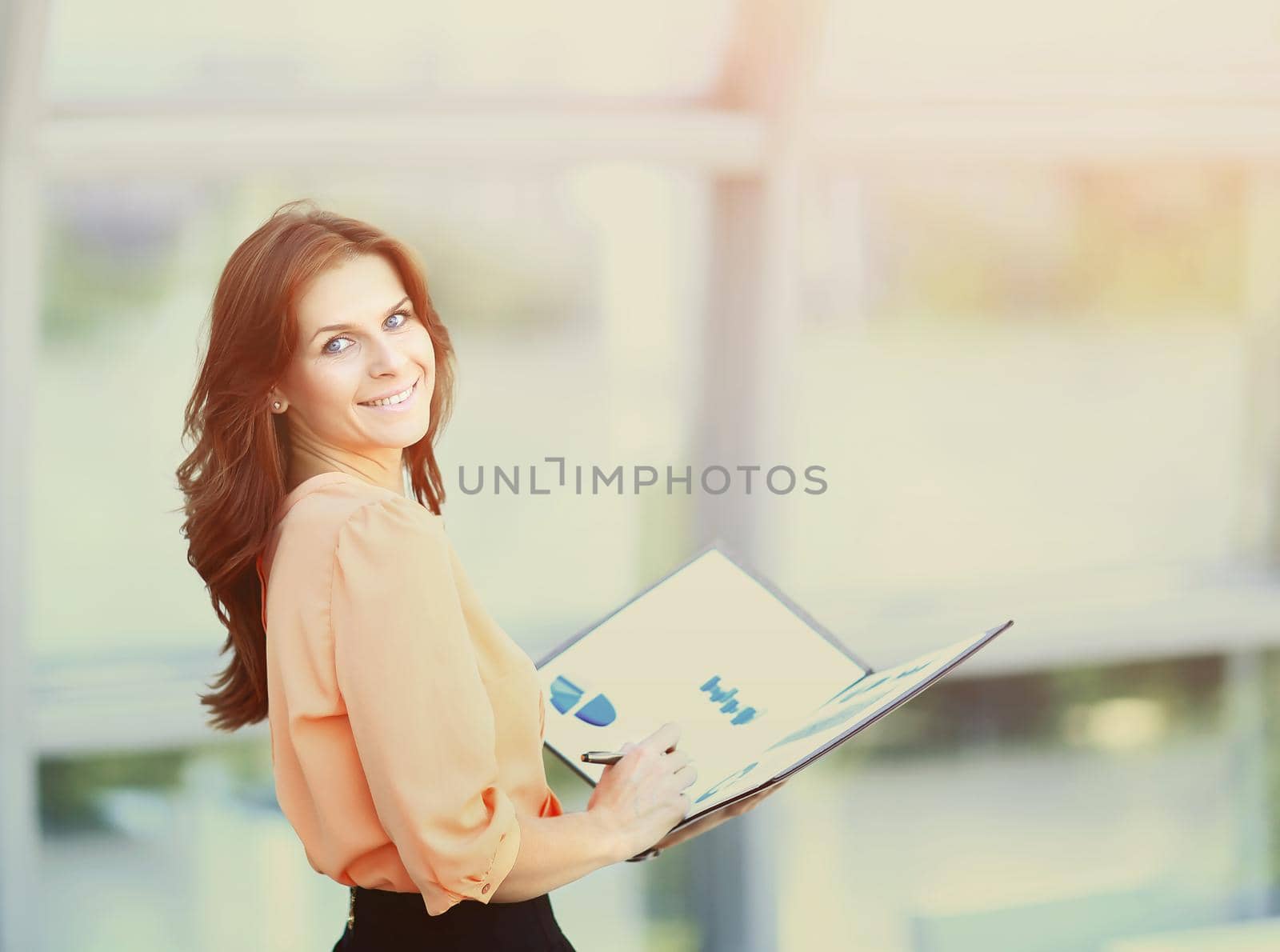 attractive business woman holding a folder with charts and diagrams in office by SmartPhotoLab