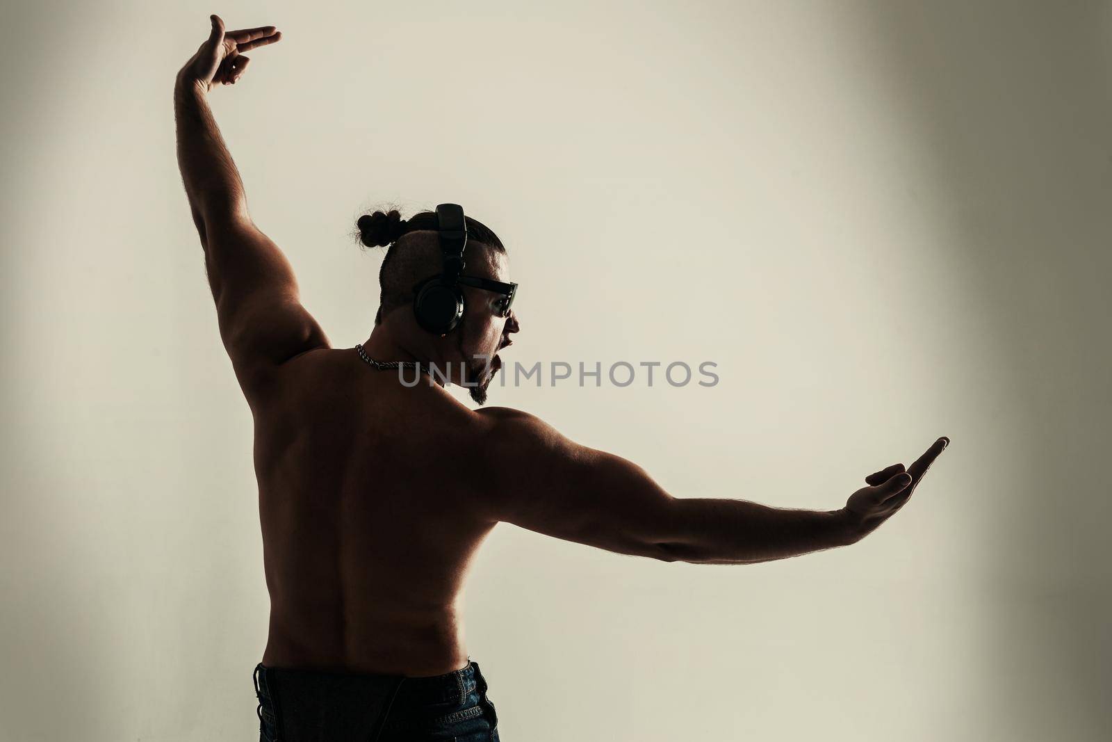 rear view - creative rapper in the headphones and dark glasses performs a rap song .photo on a light background and has an empty space for your text