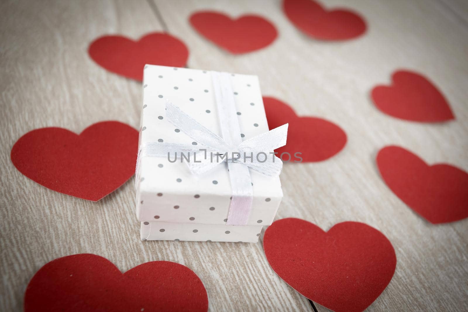 red hearts and gift box on light wooden background. photo with copy space