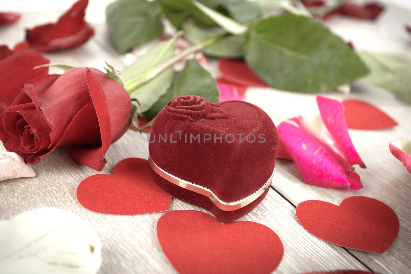 ring in the box and rose on a light wooden background. photo with copy space