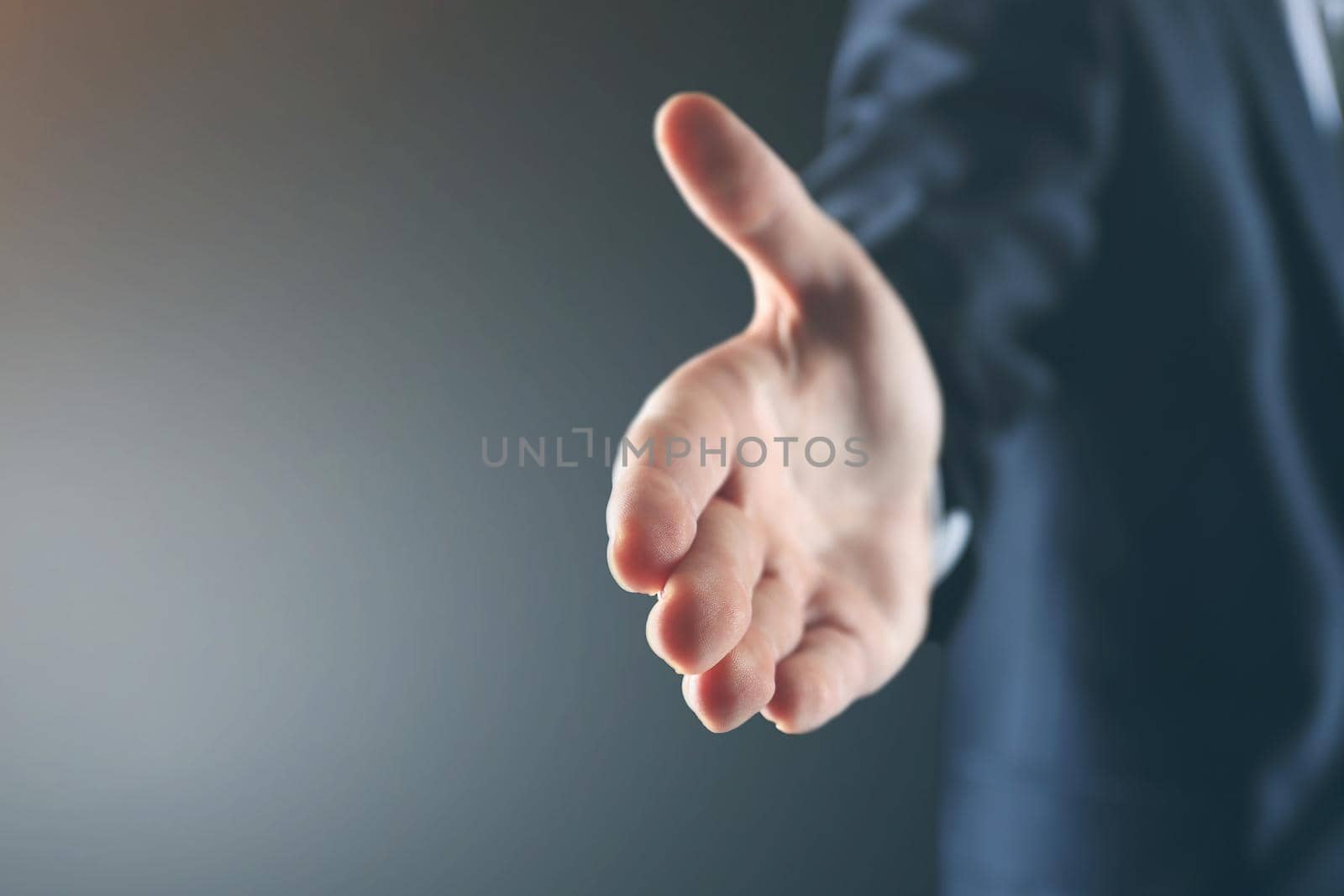 Business man with an open palm ready to strike a deal on a black background