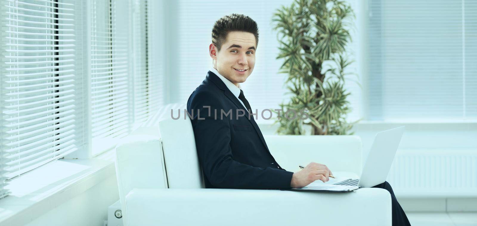 businessman in black business suit sitting behind a Desk in the spacious office