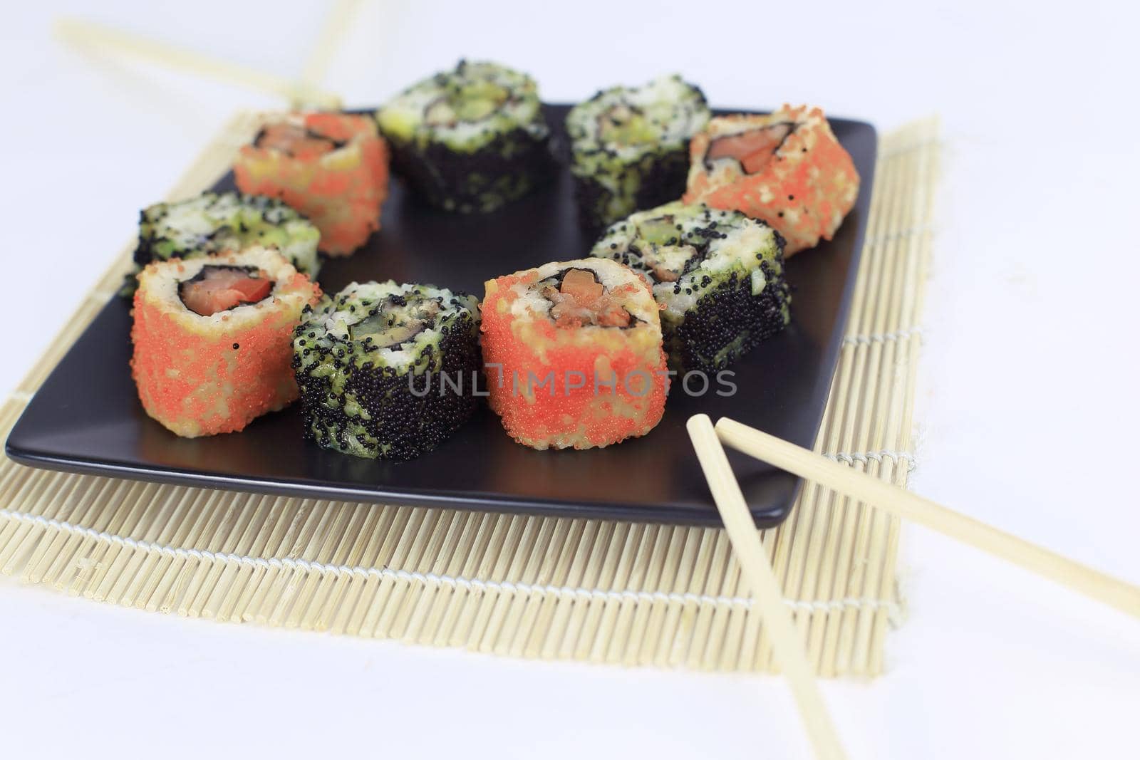 Sushi Set - different types of Maki sushi and chopsticks on a black plate.isolated on white