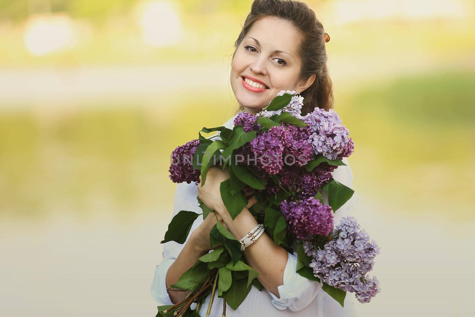 happy pregnant woman with bouquet of lilacs on the background of a Park in a autumn day. the photo has a empty space for your text