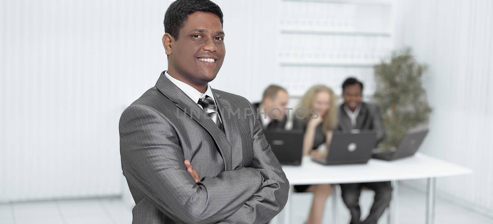 portrait of successful young businessman on background of office.