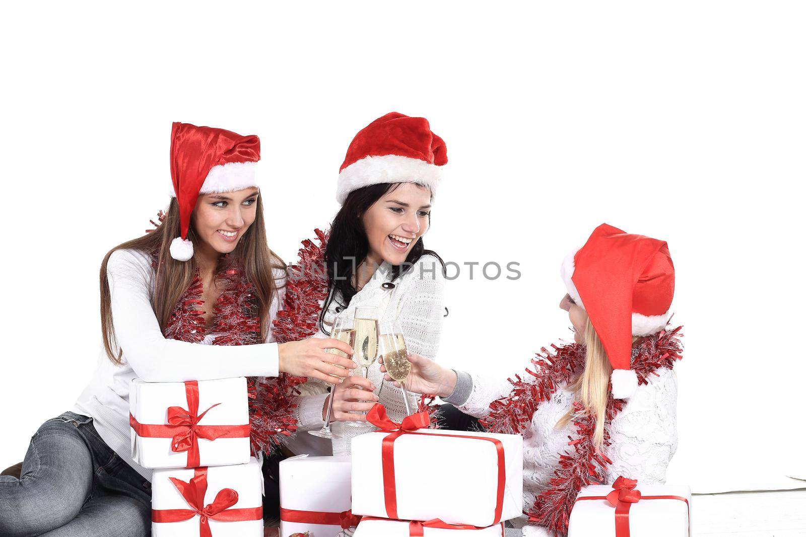 three young women in hats of Santa Claus with Christmas gifts and glasses of champagne.photo with copy space