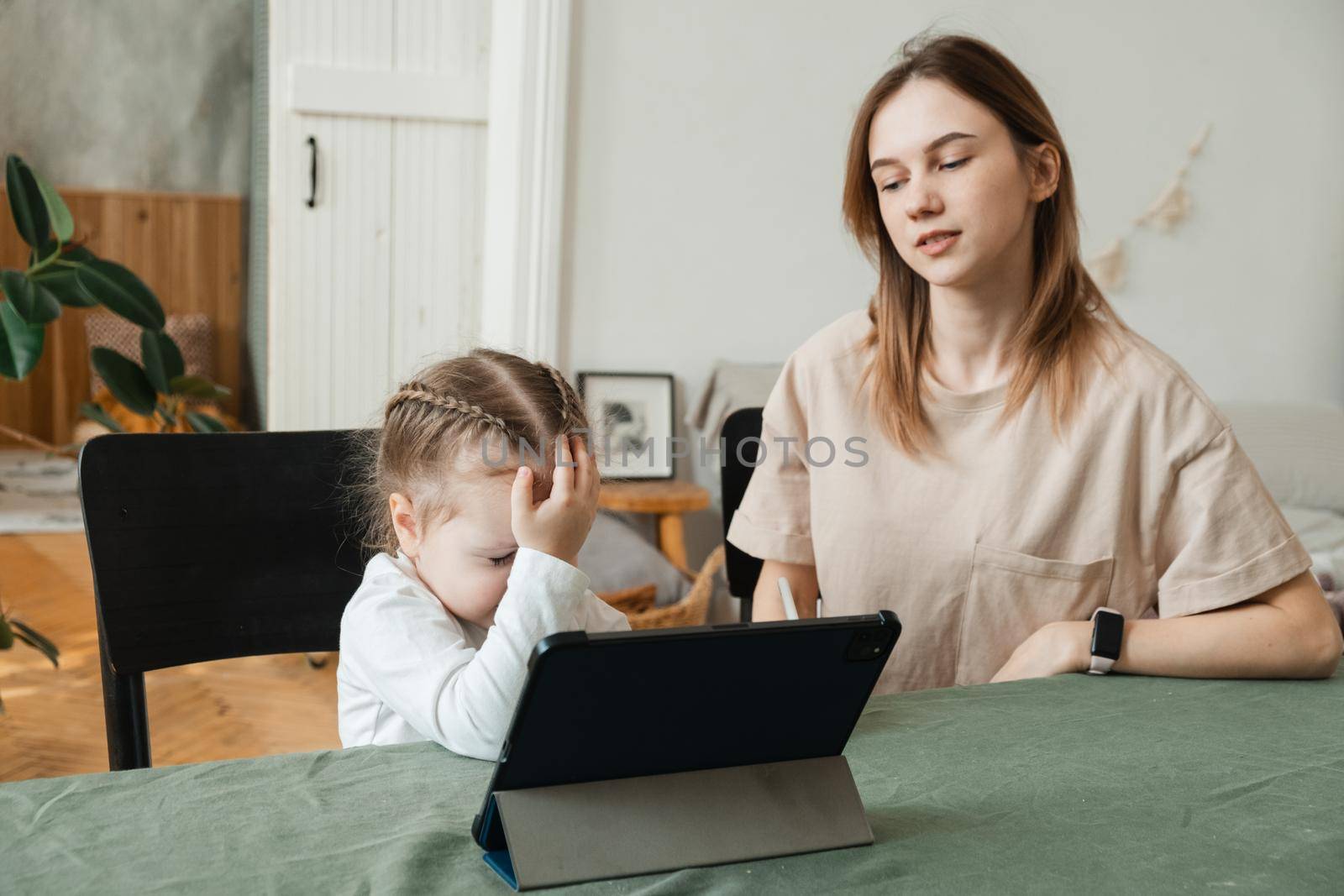 The little girl does not understand how to do homework or solve a problem. Stressed mother homeschooling with her child during coronavirus, Covid-19 outbreak quarantine. Self isolation, social distancing concept. by etonastenka