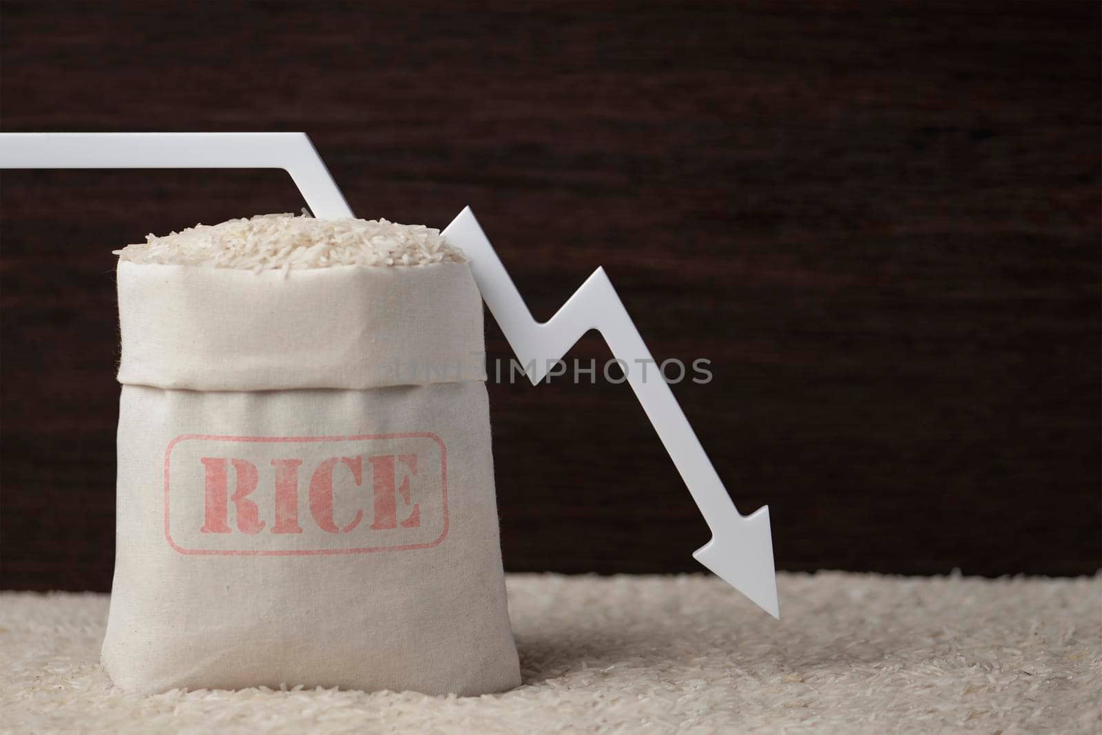 Rice harvest. Poor agricultural crops, food shortages, world hunger. A bag of rice on a brown background with a white arrow pointing down