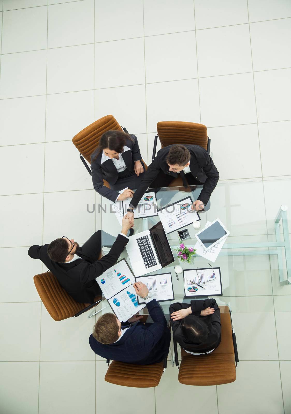 business team and reliable business partners shake hands after a debate on the new Finance contract at a Desk by SmartPhotoLab