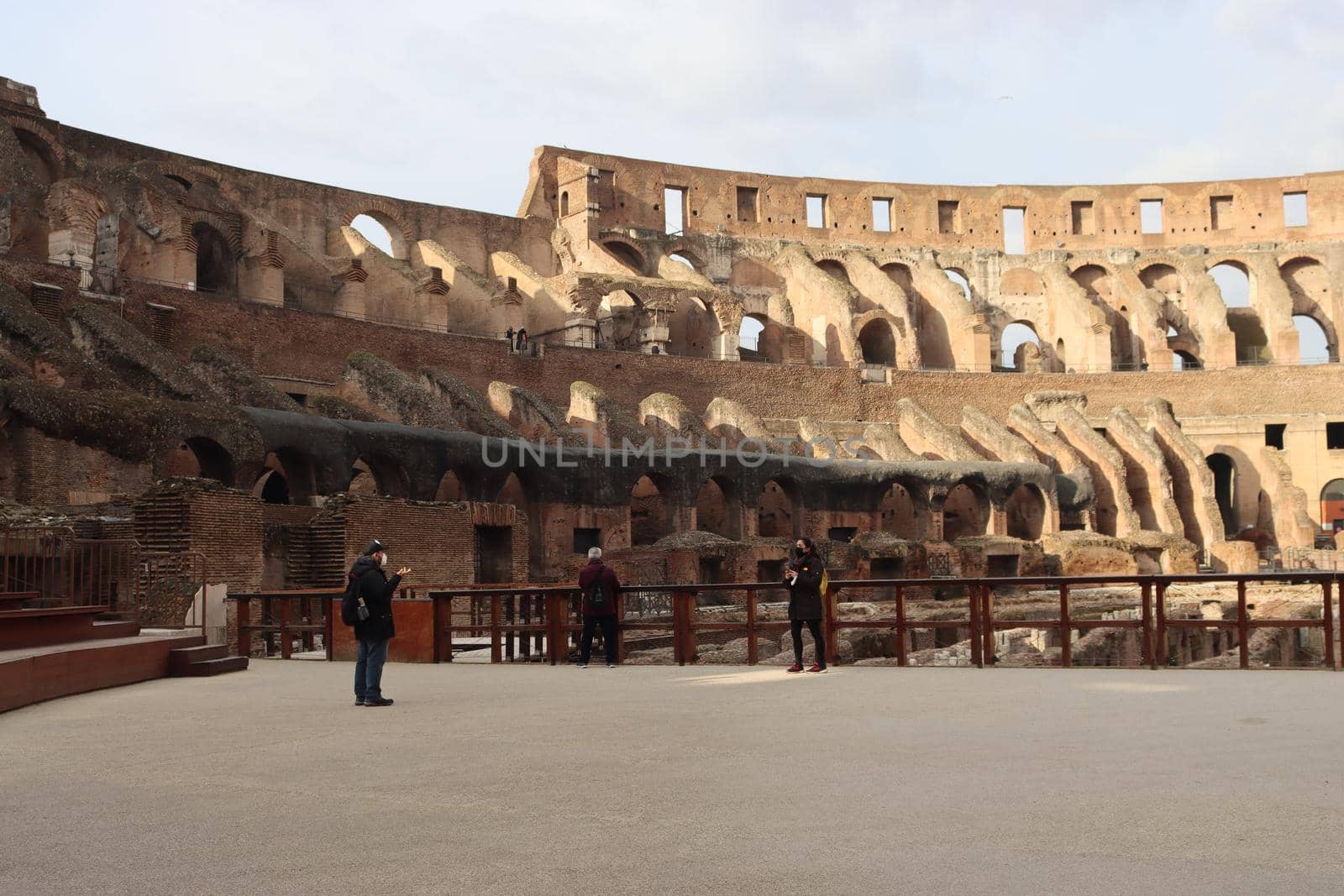 ROME, ITALY - February 05, 2022: Panoramic view around the Colosseum in city of Rome, Italy. Cold and gray sky in the background. Macro photography of the green parks with the old buildings.