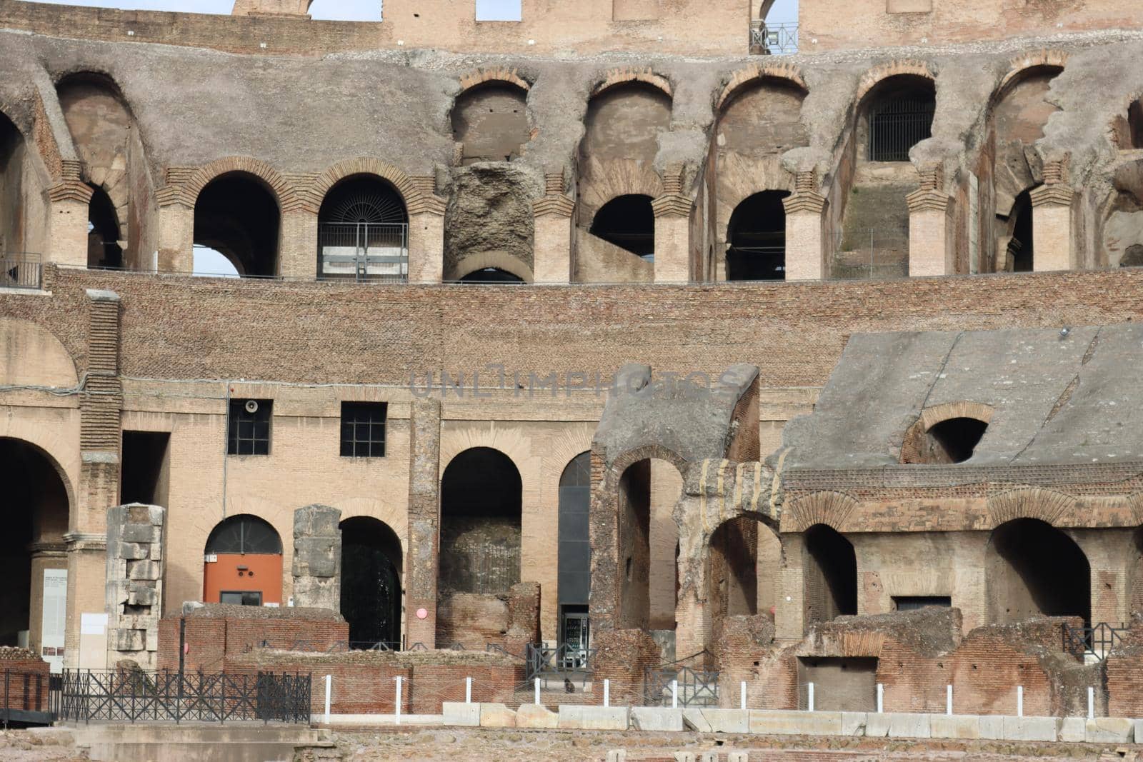 ROME, ITALY - February 05, 2022: Panoramic view around the Colosseum in city of Rome, Italy. Cold and gray sky in the background. Macro photography of the green parks with the old buildings.