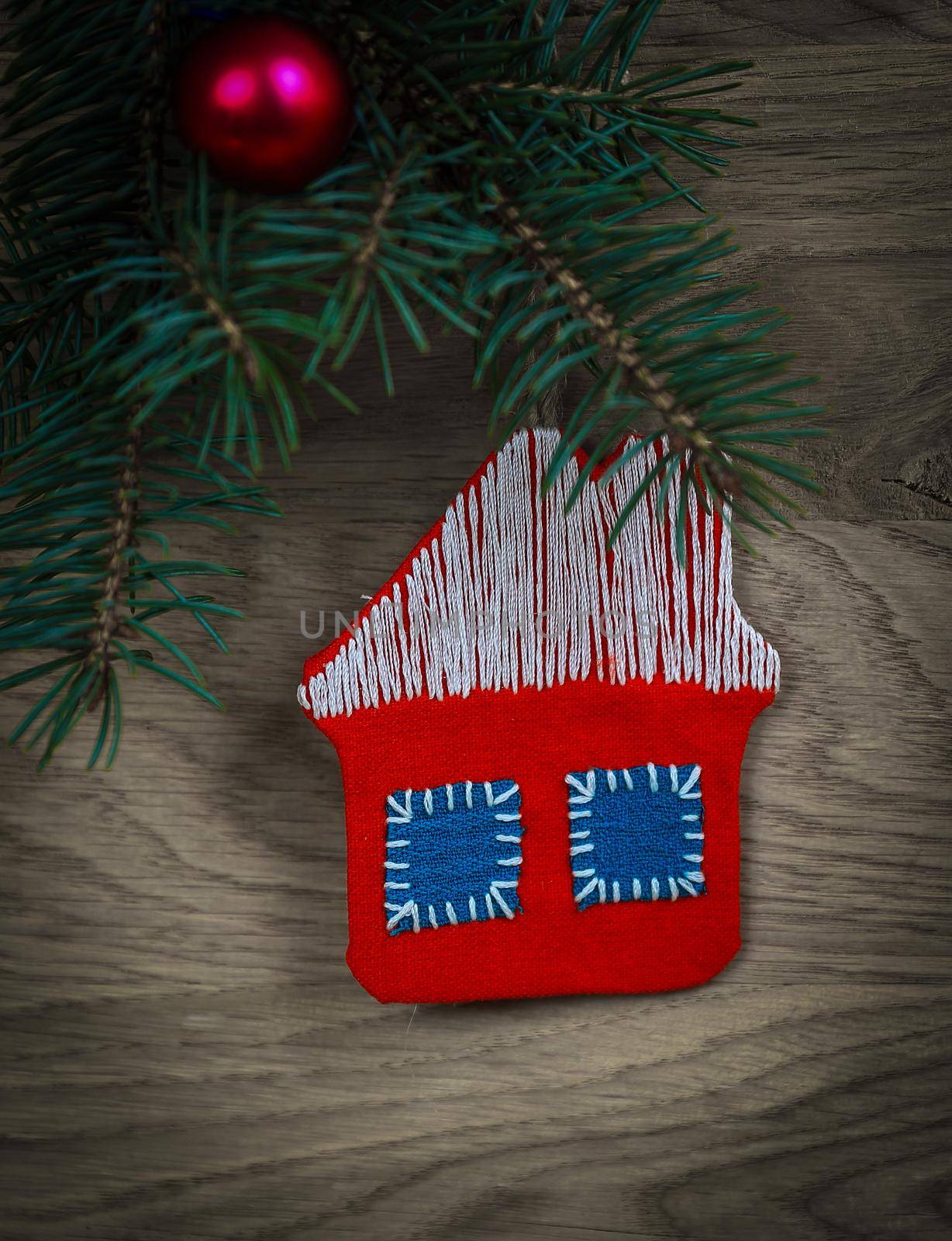 concept of Christmas.knitted house and pine branch on wooden ba by SmartPhotoLab