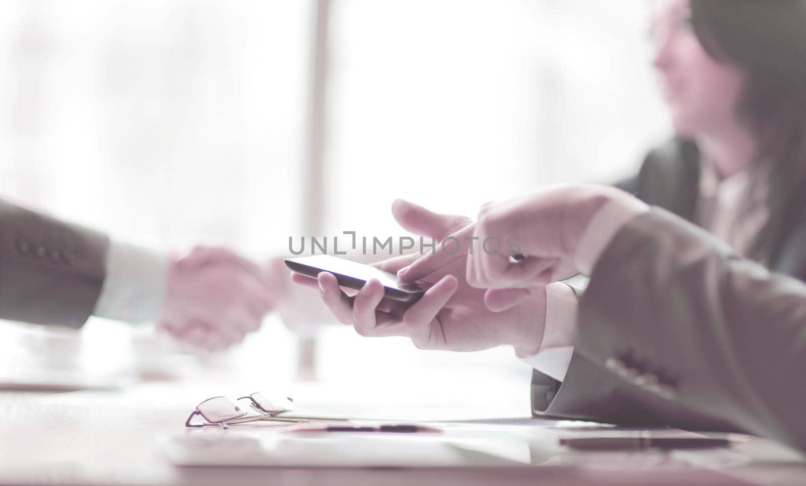 close up.a businessman uses a smartphone during a business meeting. business concept