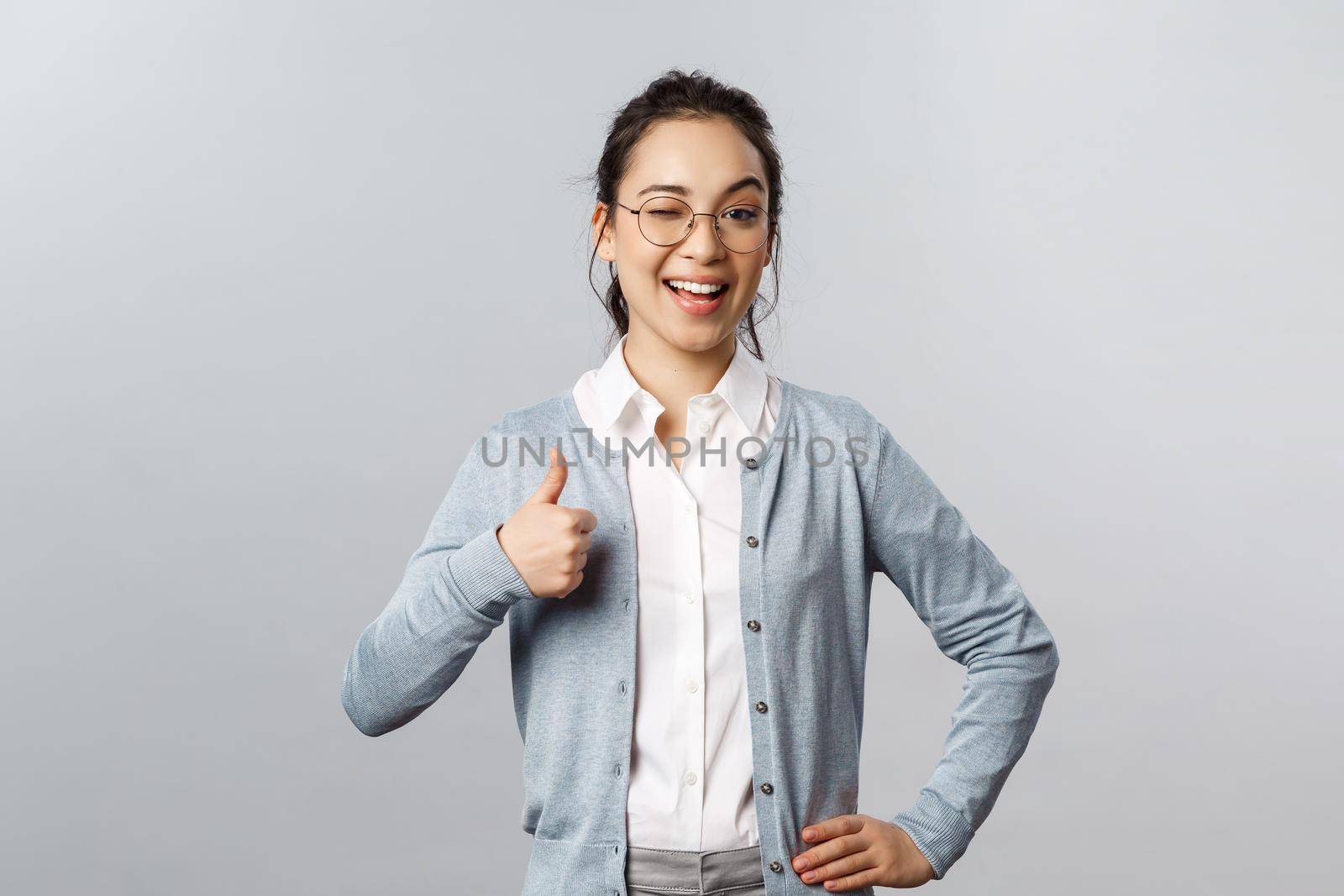 Advertisement, education and people concept. Girl guarantee you will like product. Potrait of lovely asian woman in glasses assure all good, show thumb-up in approval, recommend company service by Benzoix