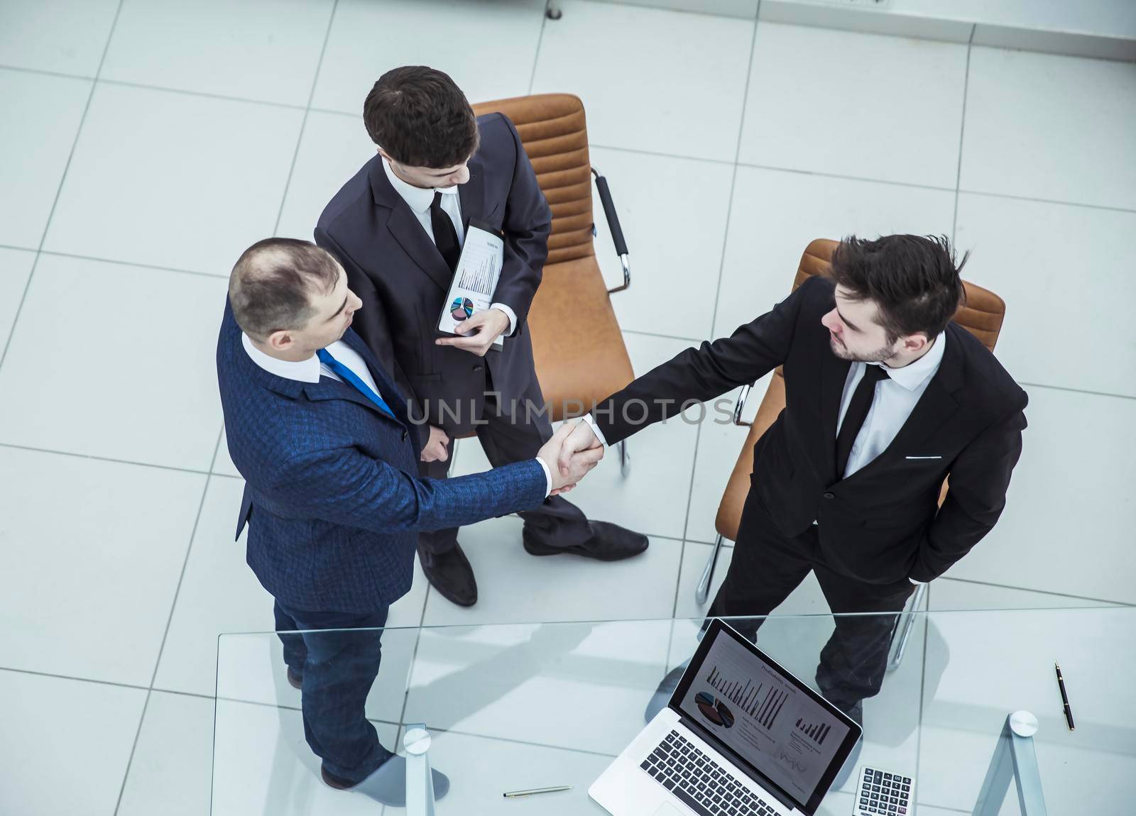 assistant with financial documents and business partners shake hands before starting a business meeting