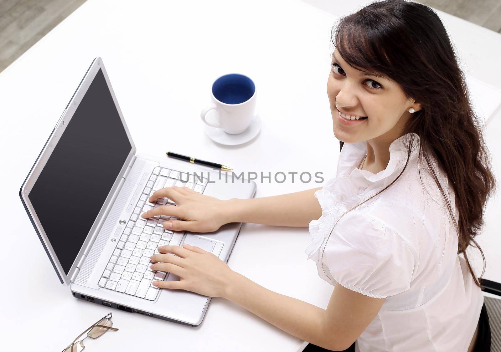 closeup. young employee sitting behind a Desk.isolated on white