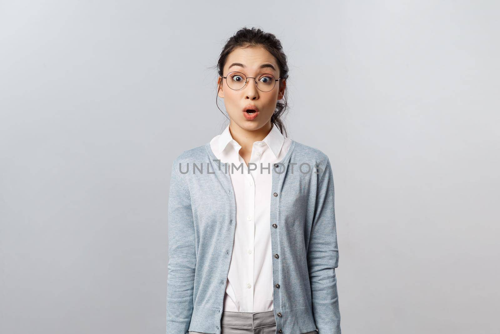 Lifestyle, people and emotions concept. Shocked, startled young asian impressed woman, stare with surprise and awe at something incredible, open mouth gasping astounded, grey background by Benzoix