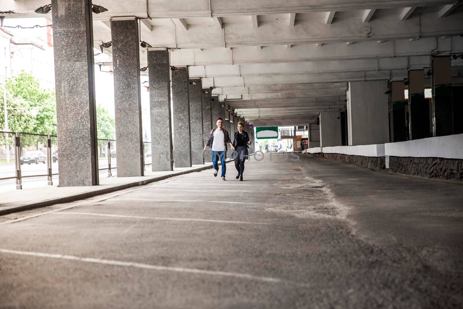 happy couple in love goes through an empty Parking garage. by SmartPhotoLab