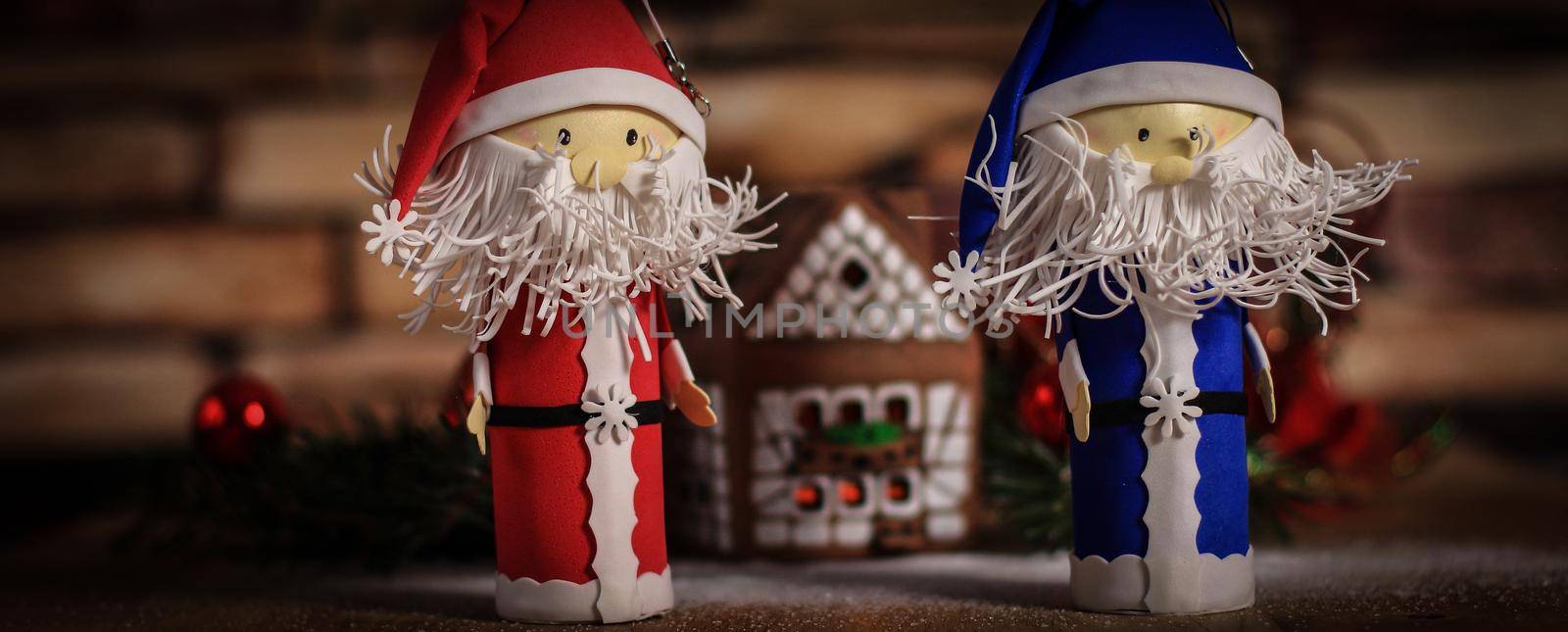 two funny Santa Claus on the background of a gingerbread house. by SmartPhotoLab