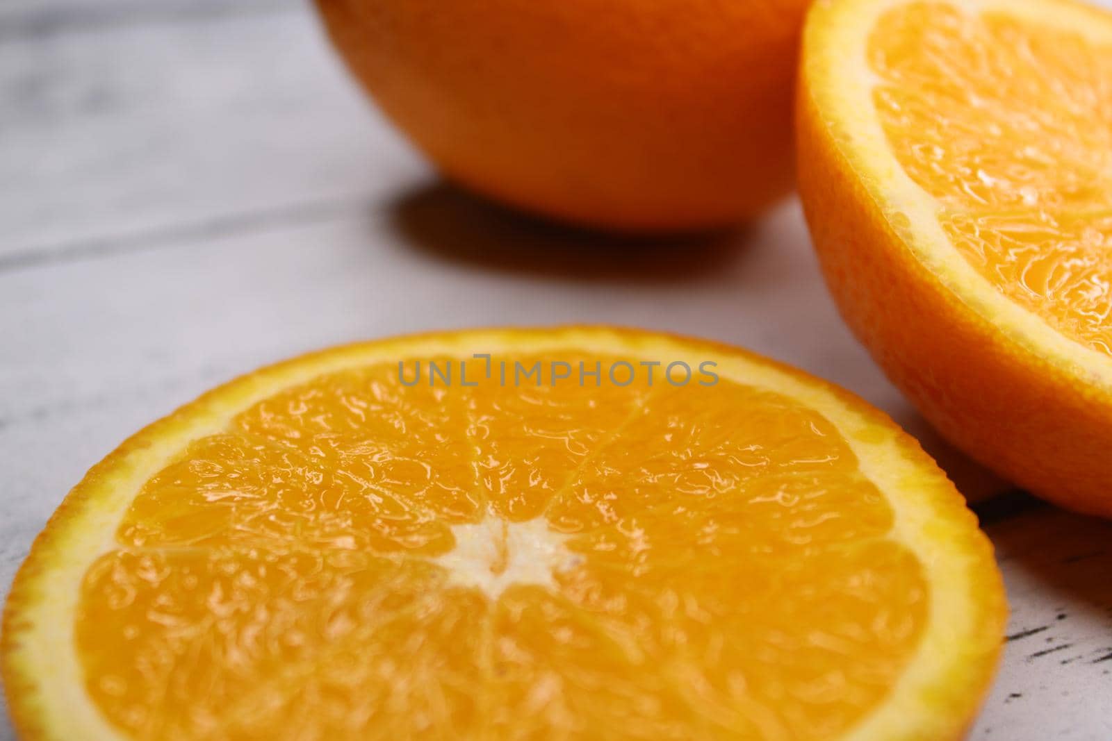 Close-up of slices and halves of oranges on a wooden table..