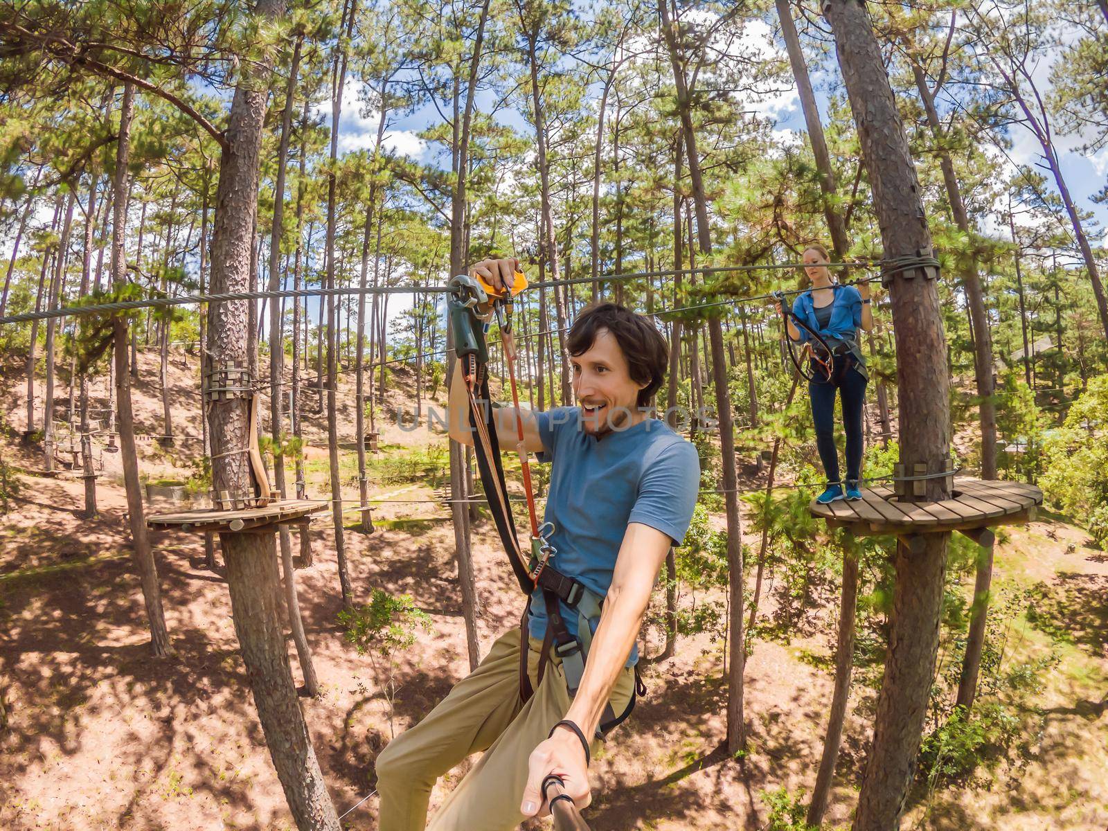 Young attractive man and woman in adventure rope park in safety equipment.