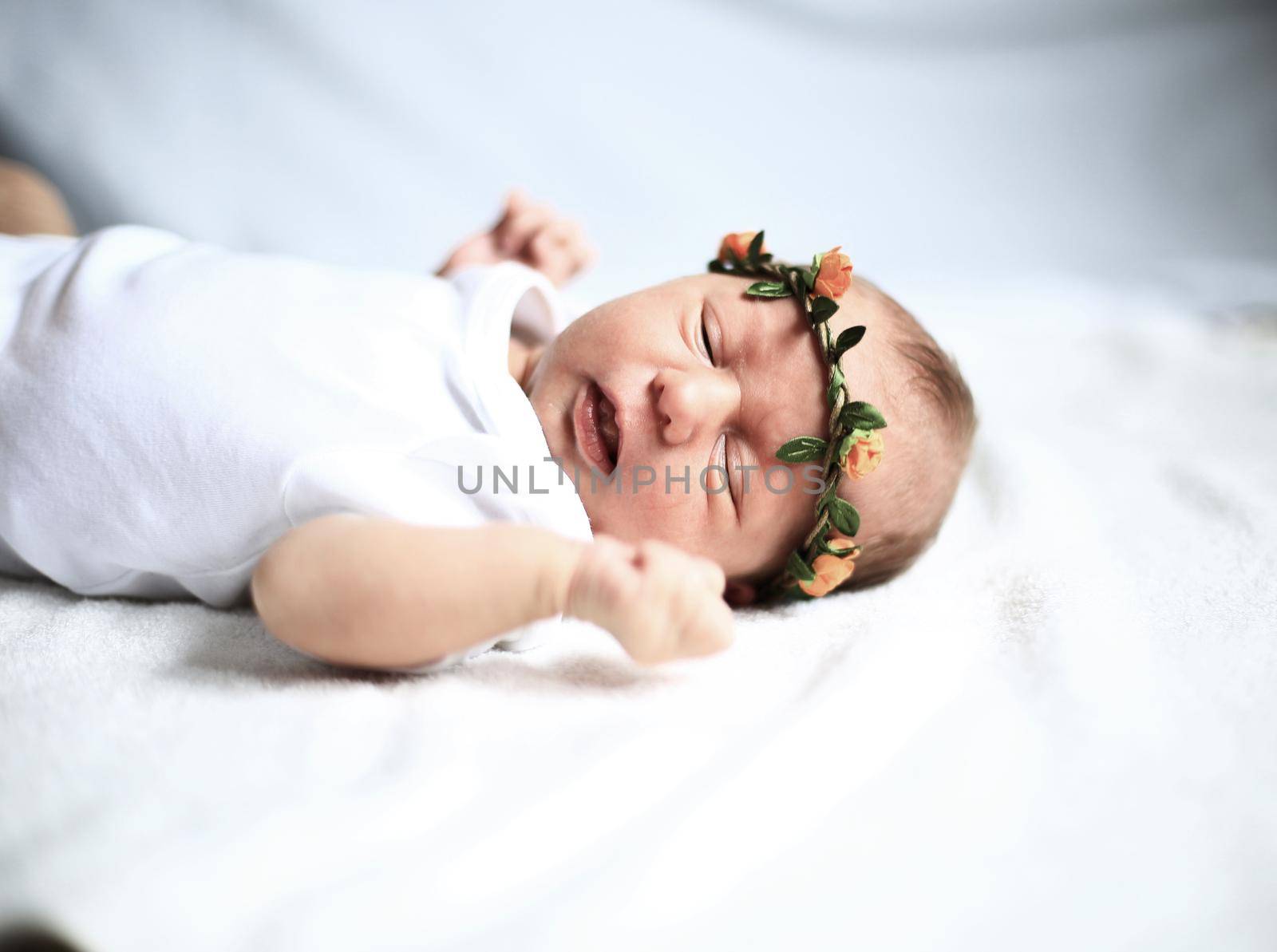 serene newborn baby in the wreath lying on the white sheet.the photo has a empty space for your text