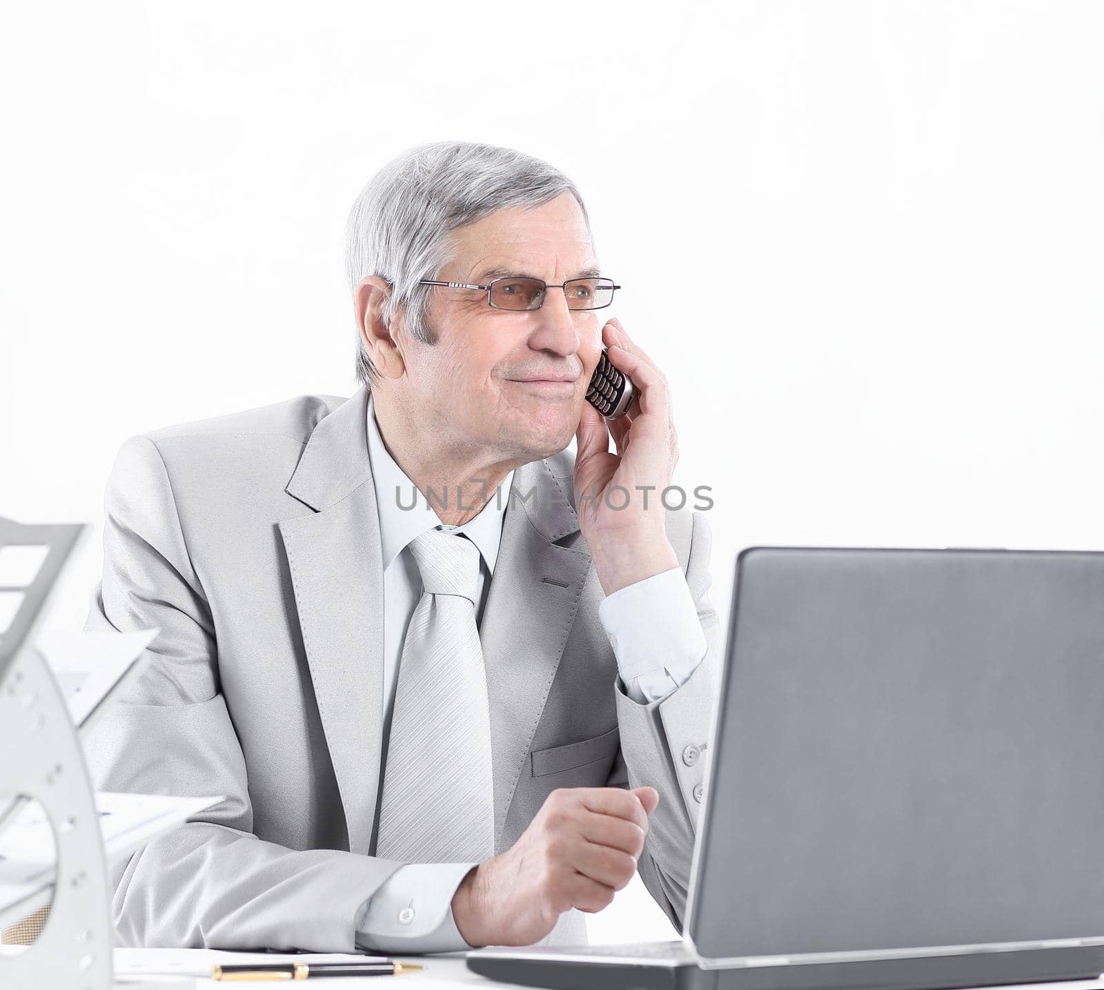 experienced businessman with mobile phone sitting at his Desk by SmartPhotoLab