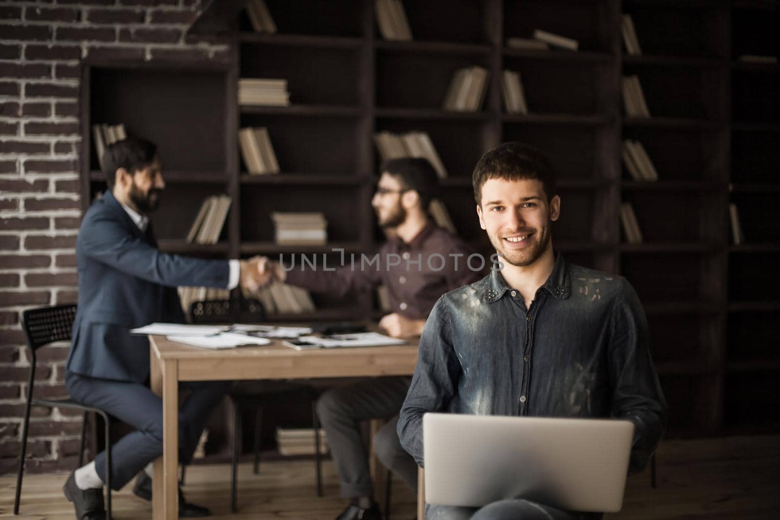 creative sales Manager with notebook on background of business partners handshaking in a modern office