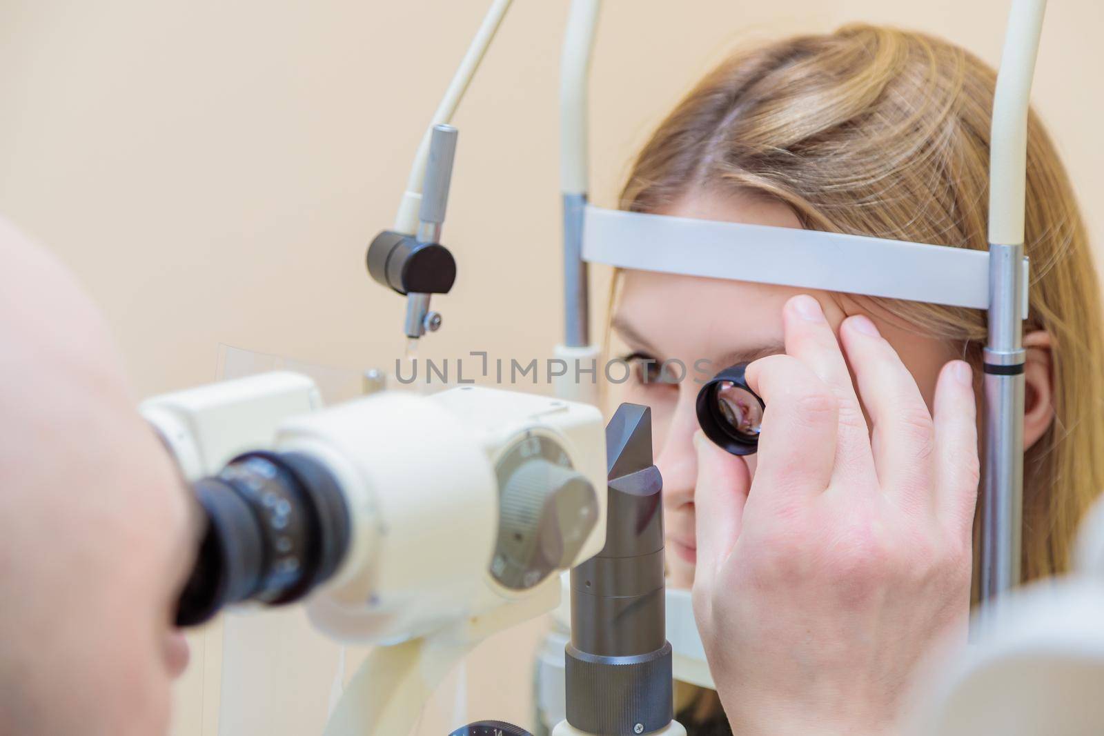 A male ophthalmologist checks the eyesight of a young girl using a modern device with a light beam.
