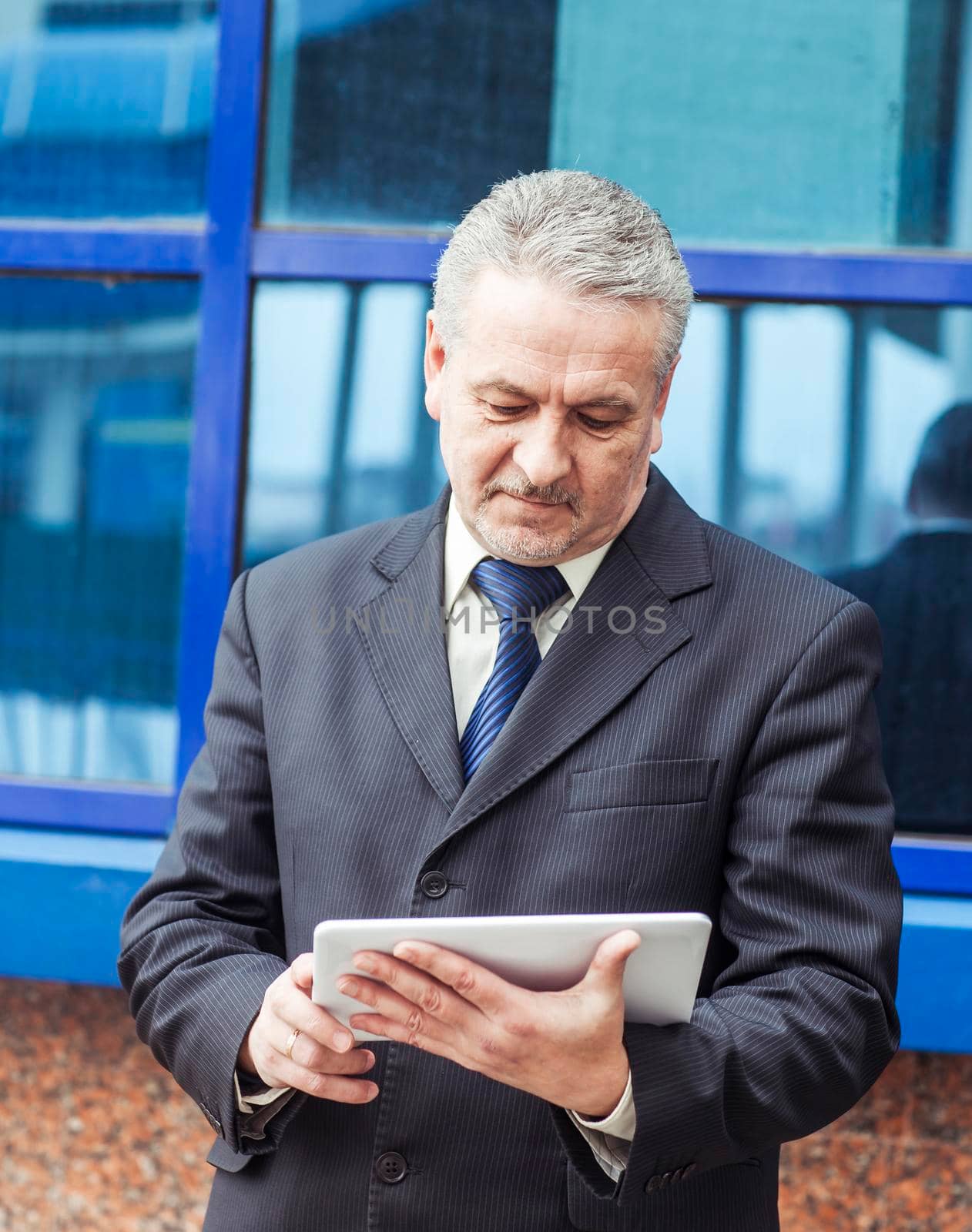 successful businessman with digital tablet on background of office building by SmartPhotoLab