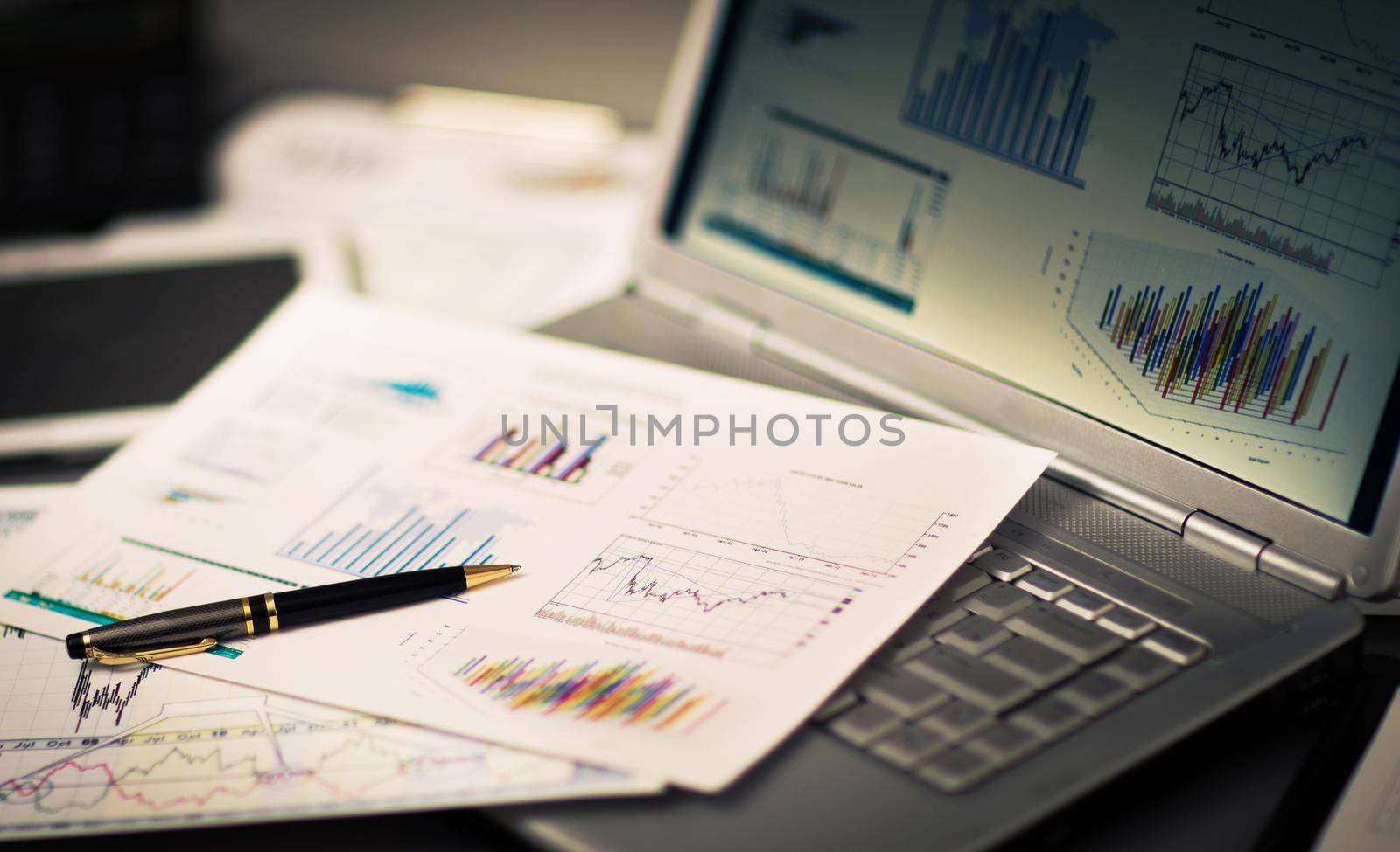 Businessman analyzing investment charts with laptop. by SmartPhotoLab