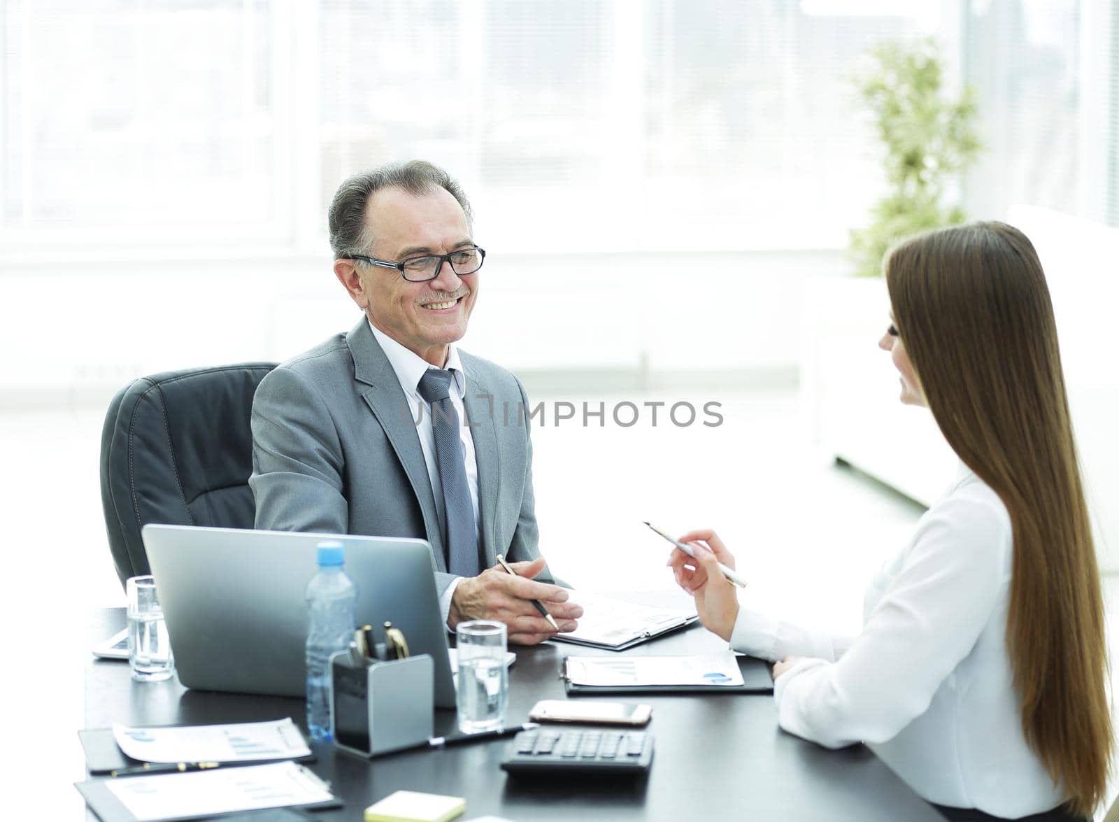 senior businessman talking to his young assistant at the Desk in the office