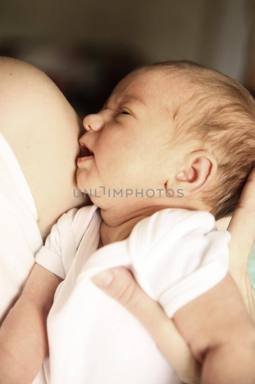 serene newborn baby in his mother's arms on the background of children's room