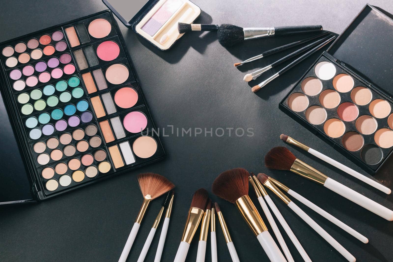 makeup brush, blush and eye shadow on black background. photo with copy space