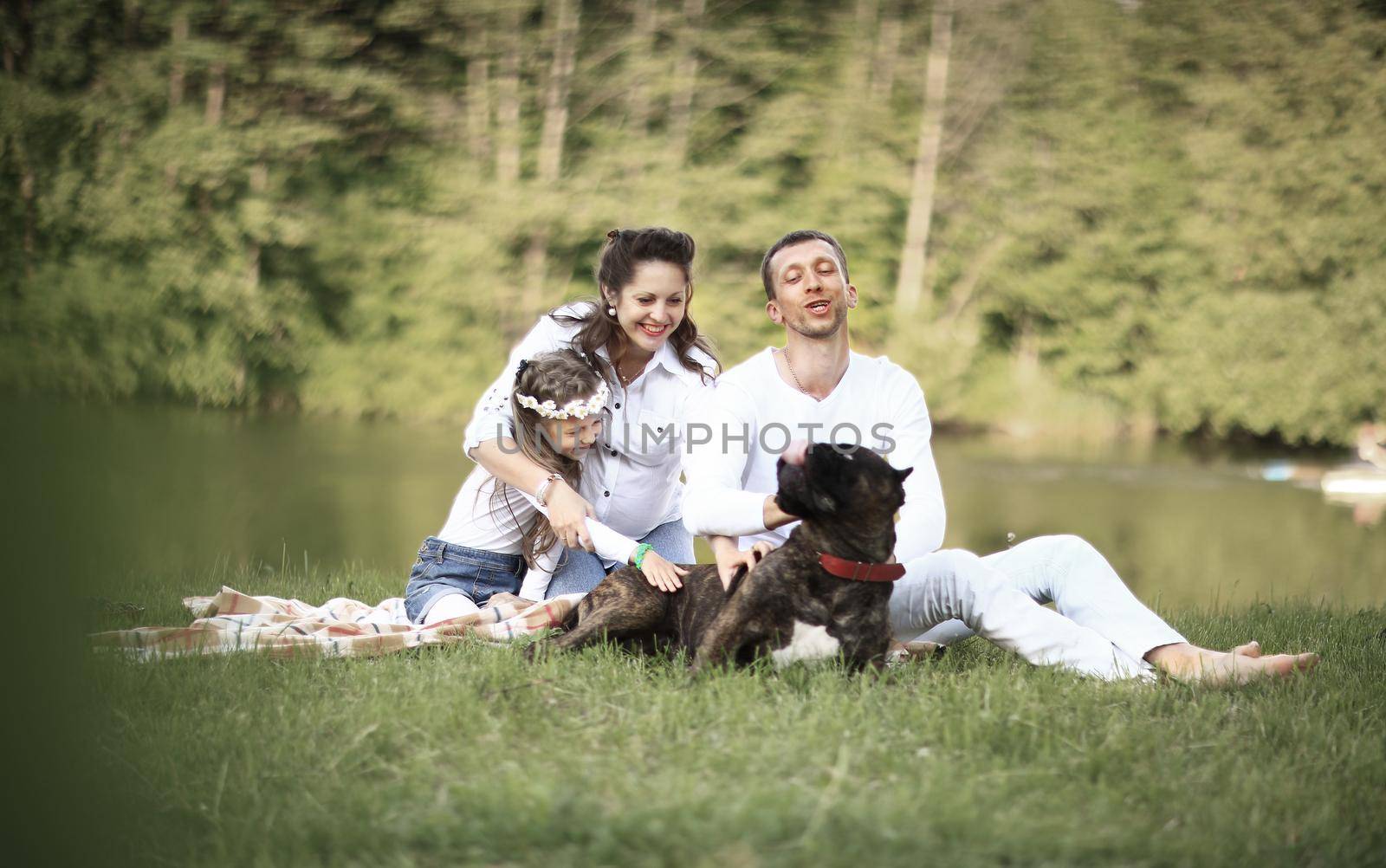 ,little daughter and their dog on a picnic by the river.the photo has a space for your text