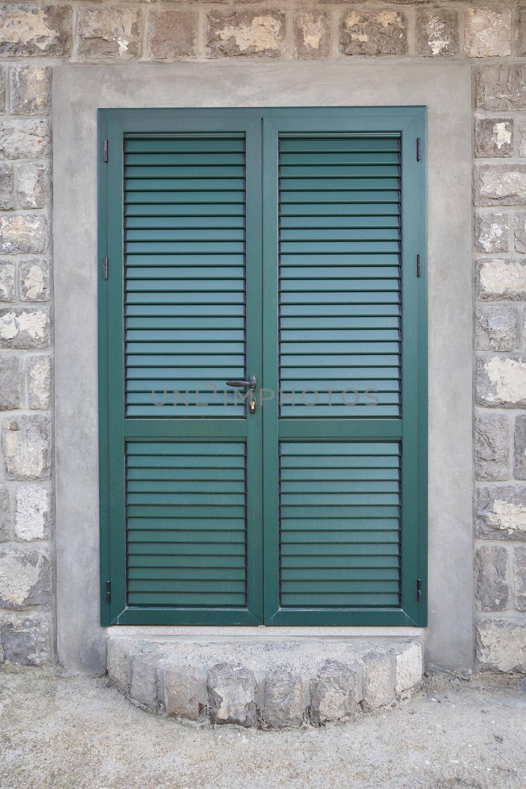 Green door with shutters at the entrance to the house.