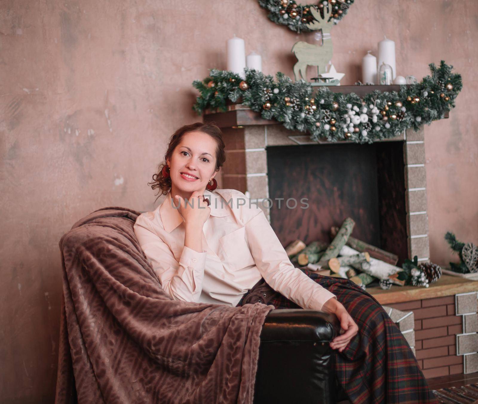 young woman sitting by the fireplace in a cozy living room. the concept of Christmas