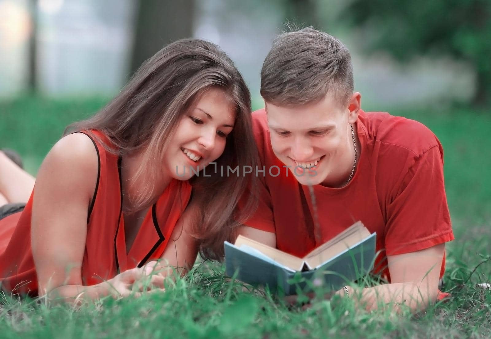 couple of students lying on the grass in the Park and reading a book by SmartPhotoLab