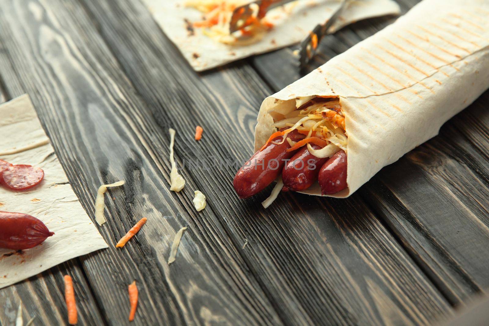 smoked sausage in pita bread on wooden background.
